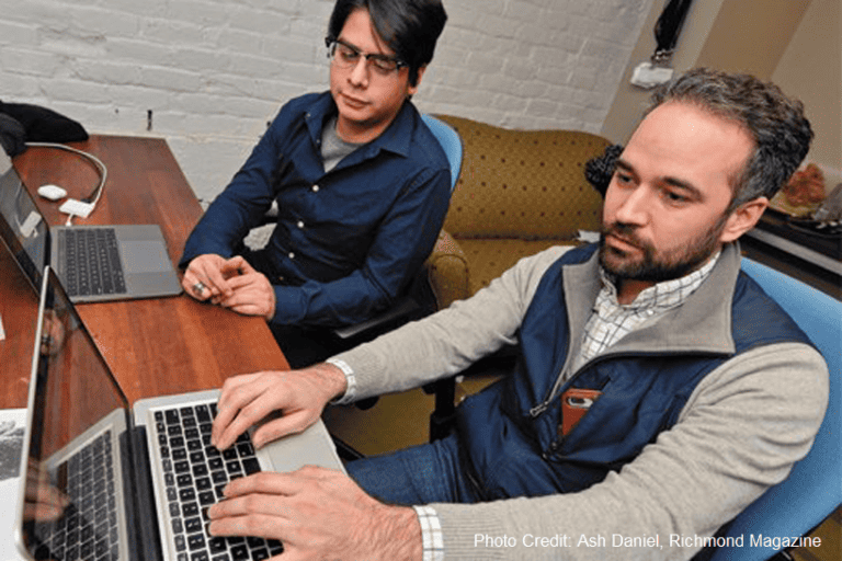 Two men sit in front of laptops, working together to figure out a transformative tech talent strategy