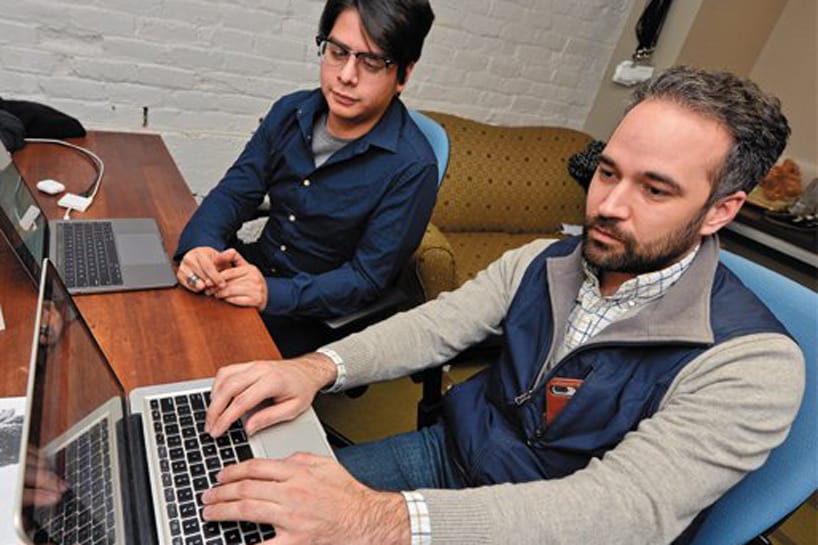 Two men sit in front of laptops, working together to figure out a transformative tech talent strategy
